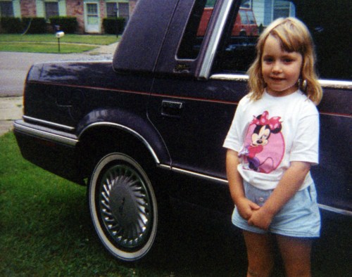 Young girl standing next to car